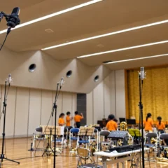小学校のホールに複数のマイクを配置し、金管楽器の出張レコーディングを準備している様子